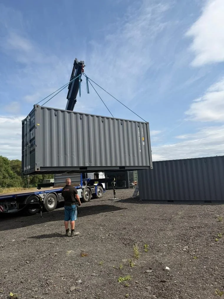 A container being craned into position beside the existing row