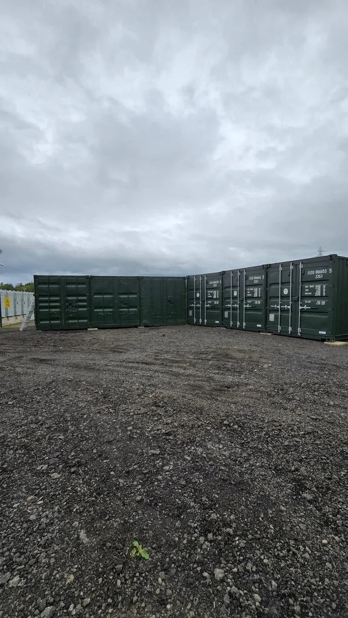 Green containers around the open gravel yard