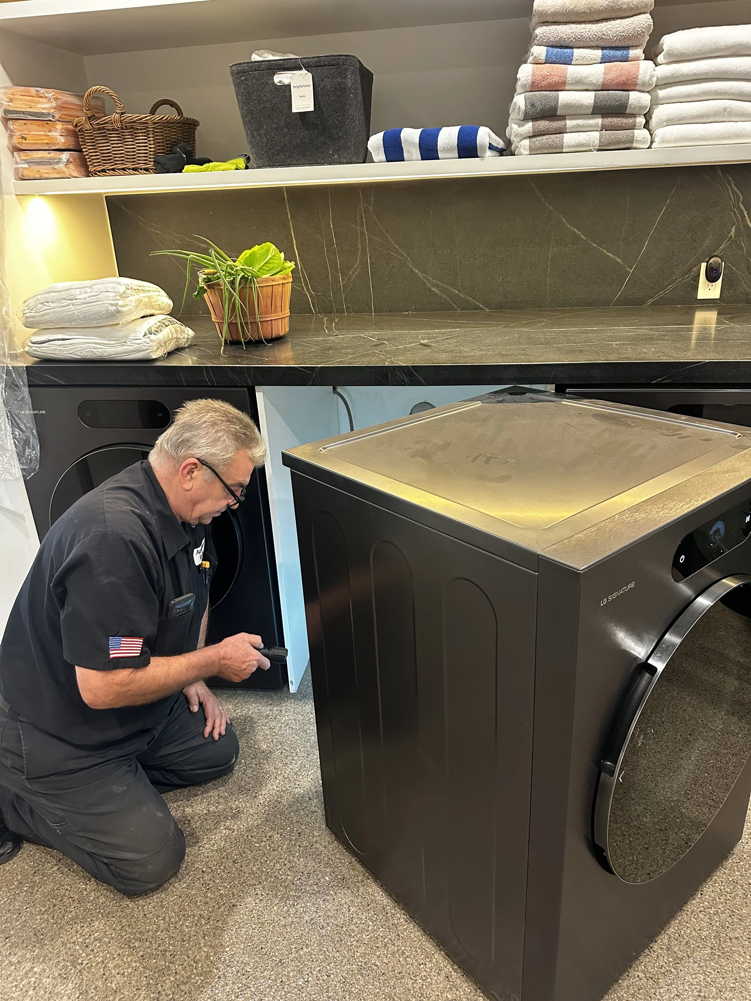 Technician inspecting an LG Signature dryer in a home laundry room