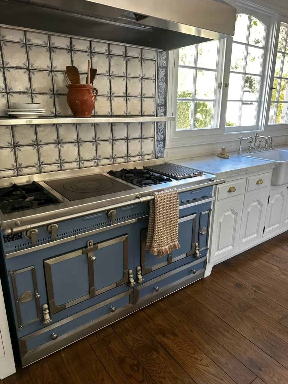 Close-up of a blue La Cornue range with a cast-iron French top and brass burner knobs