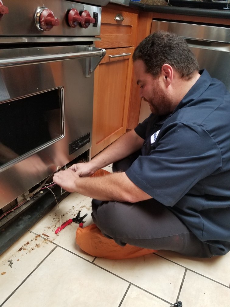 Technician fixing electrical wiring on a stainless steel oven