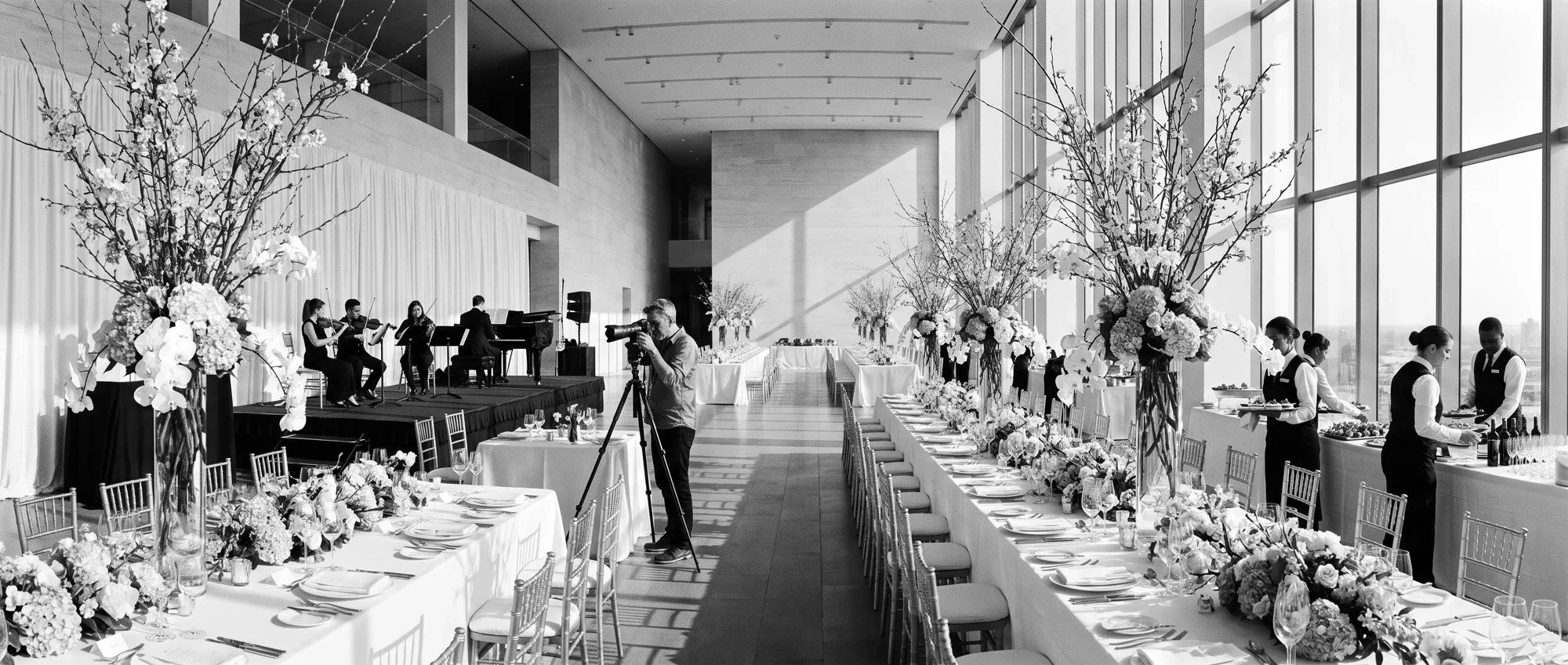 An elegant event space with catering, floral design, live entertainment and production teams preparing for guests