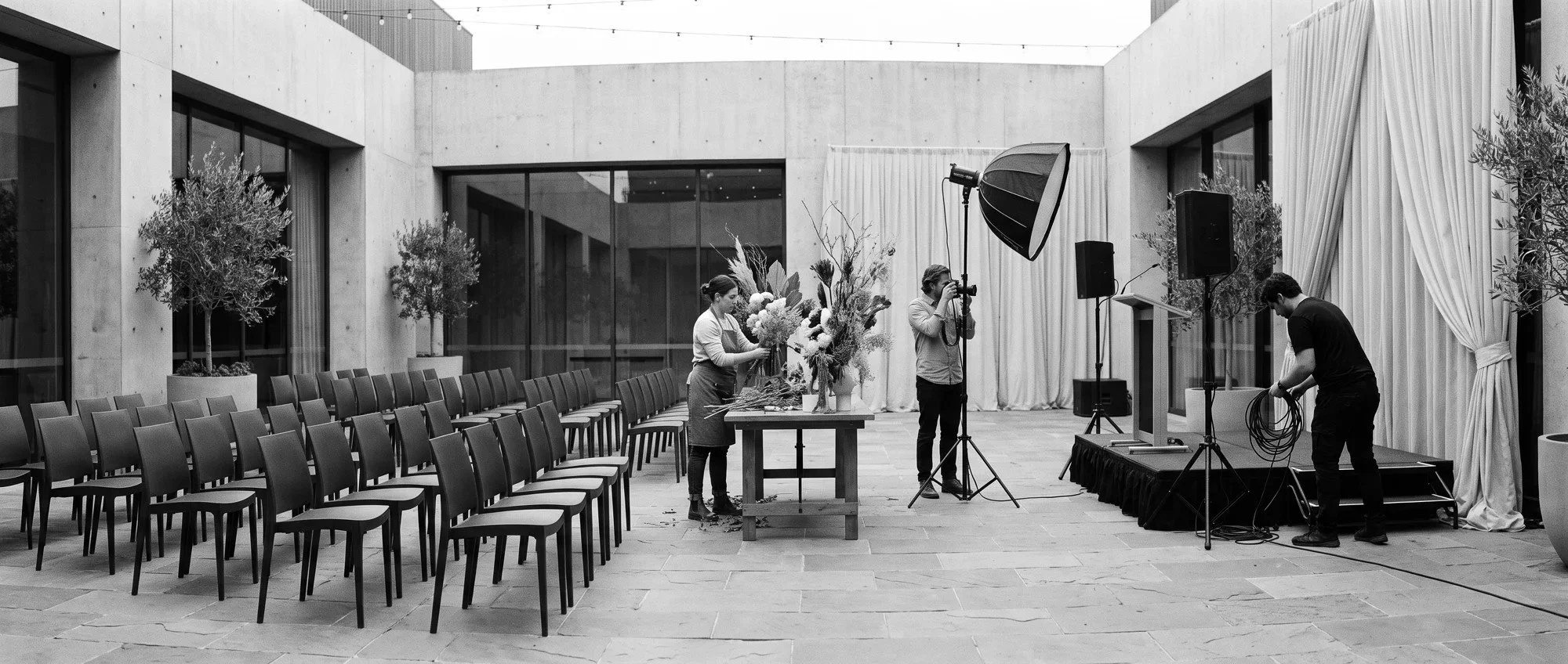 Event professionals preparing a courtyard venue, including floral design, photography and production