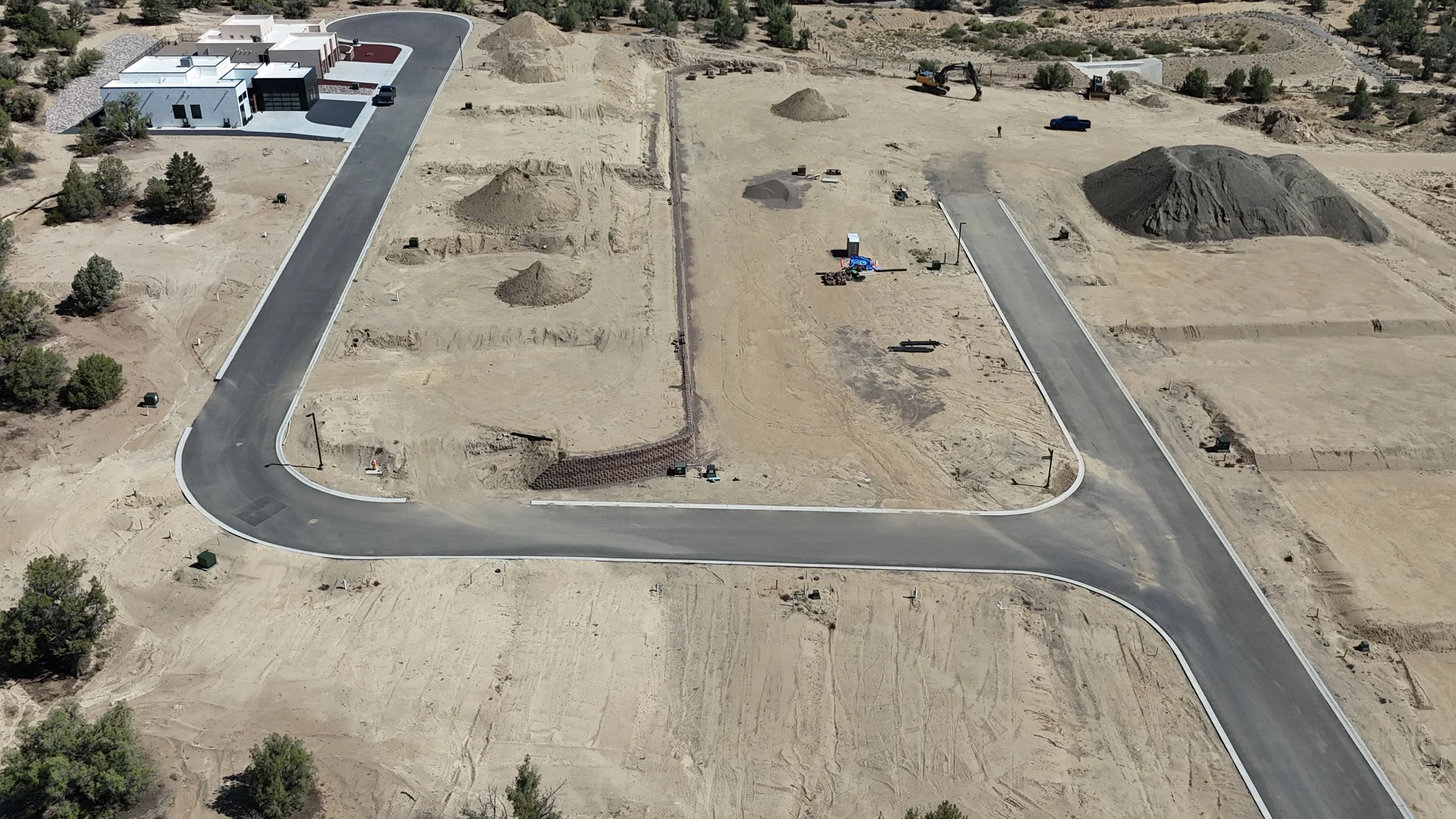 Closer drone view of Sandstone showing paved streets, graded land, homes and construction activity