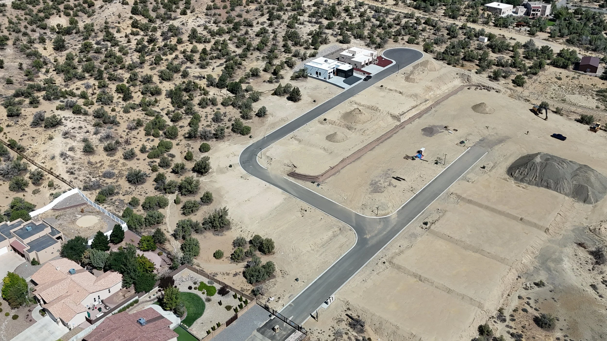 Wide drone view of Sandstone showing paved streets, developing homesites and surrounding homes and landscape