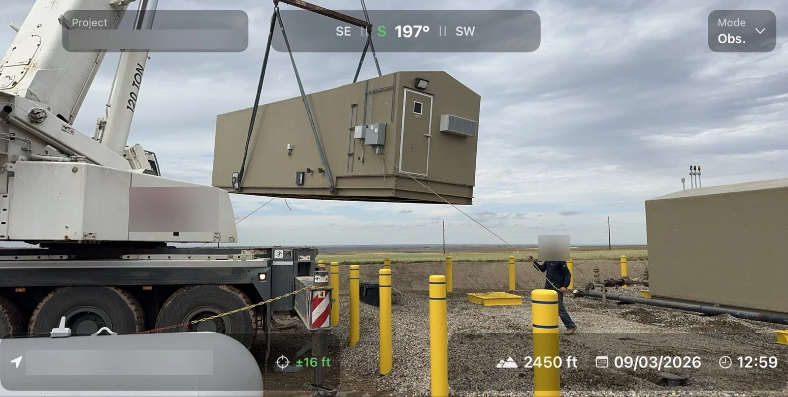 Crane lifting an equipment shelter into place on a pad