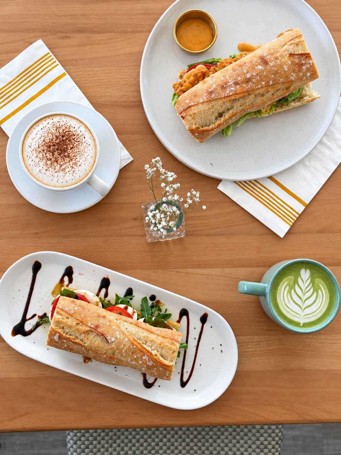 Matcha and cappuccino beside baguette sandwiches at Le Brulée