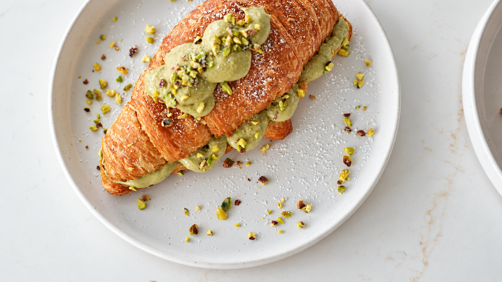 Le Brulée Pistachio Croissant filled with Italian pistachio cream and topped with crushed pistachios