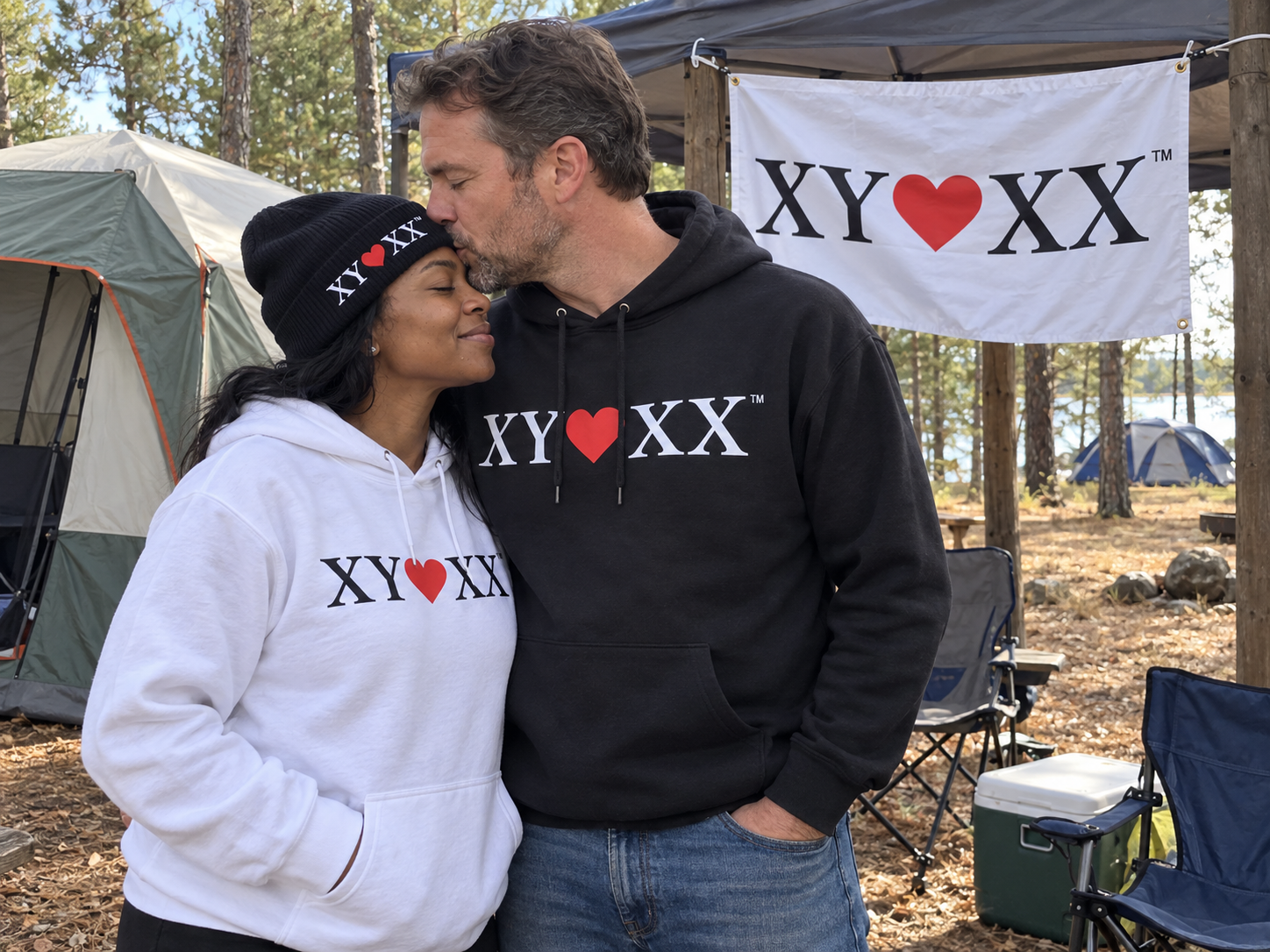 Couple wearing TSF hoodies sharing a forehead kiss at a campsite.