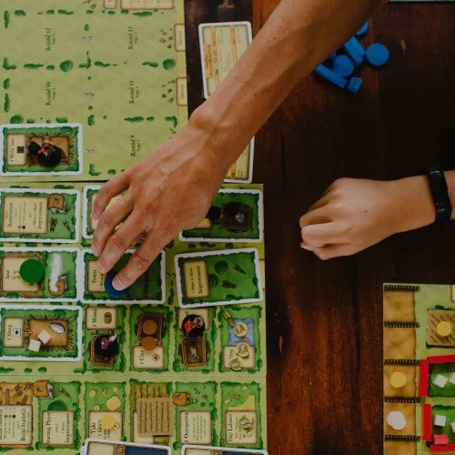 Daniel plays a board game with text 'Organic Intelligence'