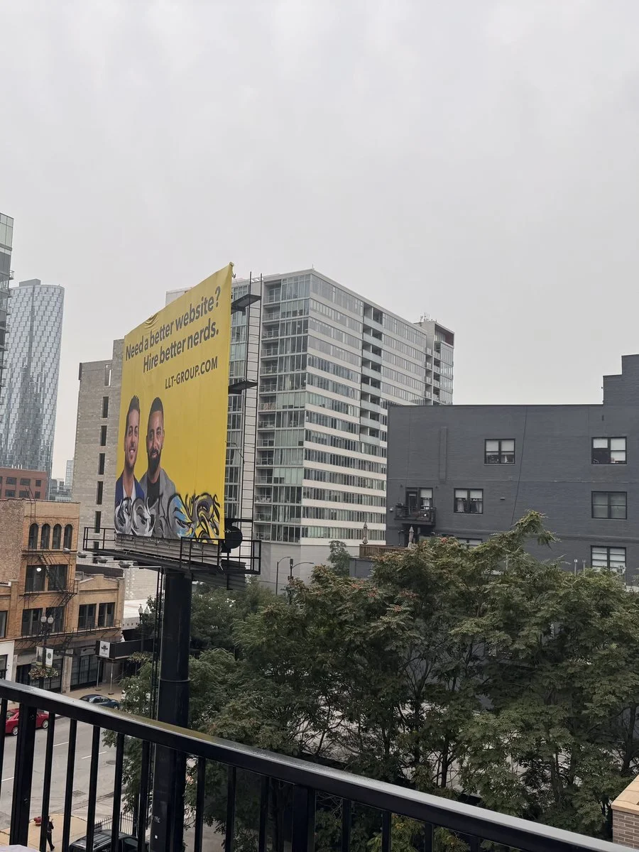A yellow billboard on a building above a downtown Chicago street
