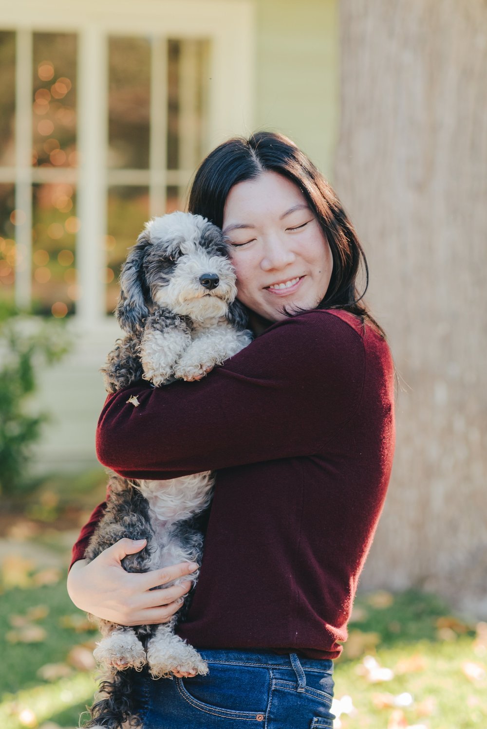 Joyce smiling as she cuddles her dog outdoors