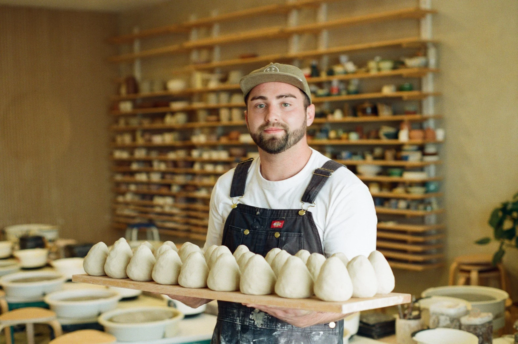 John Jaspert facing the camera and holding a board of prepared clay