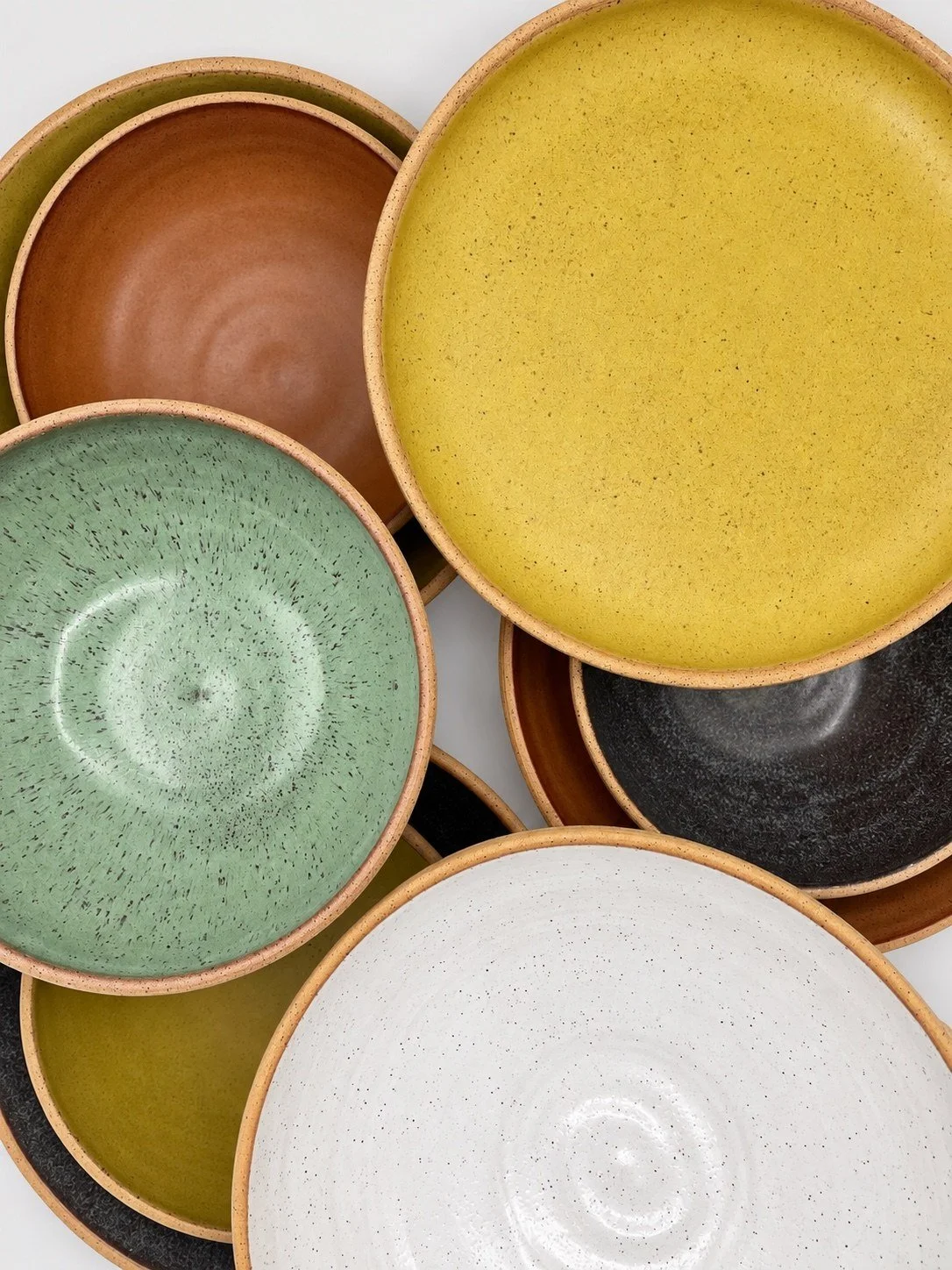 Overlapping Ochre, sage green, white and dark dinner plates
