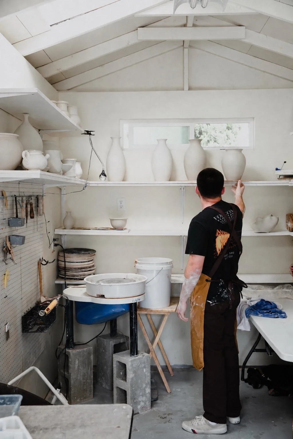 John among wheels and shelves of pottery in his Vista studio