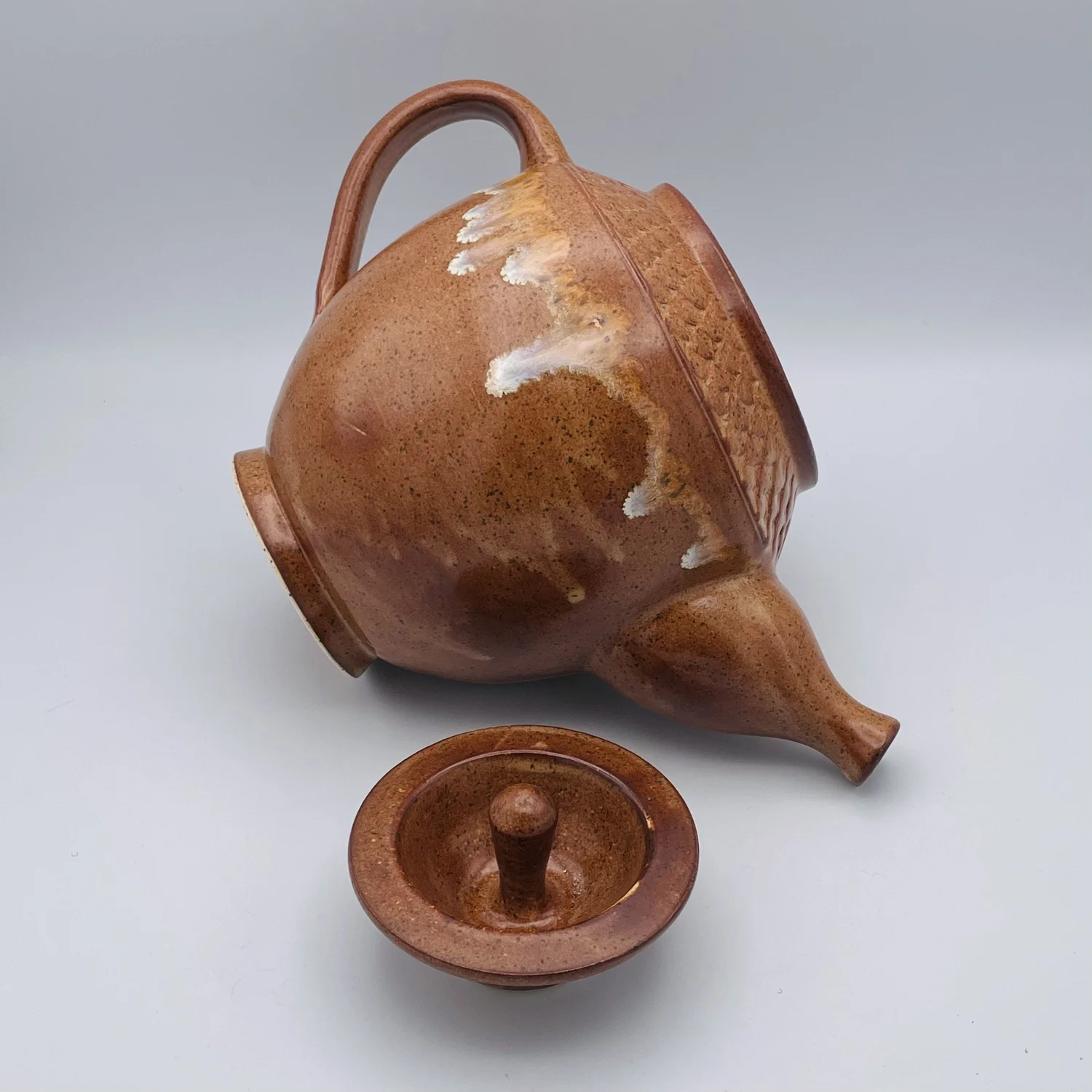 Amber glazed teapot with its lid beside it