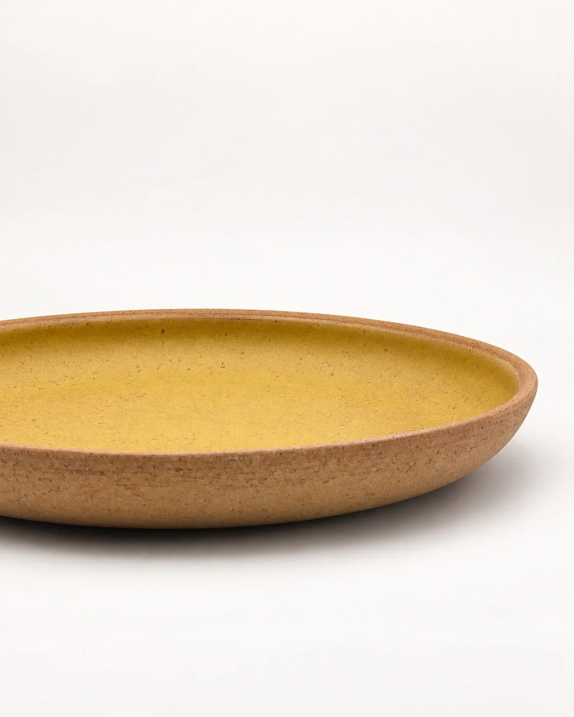 Ochre plate with exposed speckled buff clay exterior