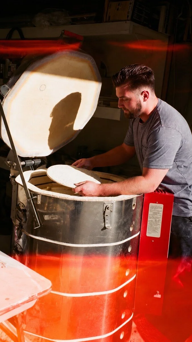 John loading pottery into an open kiln