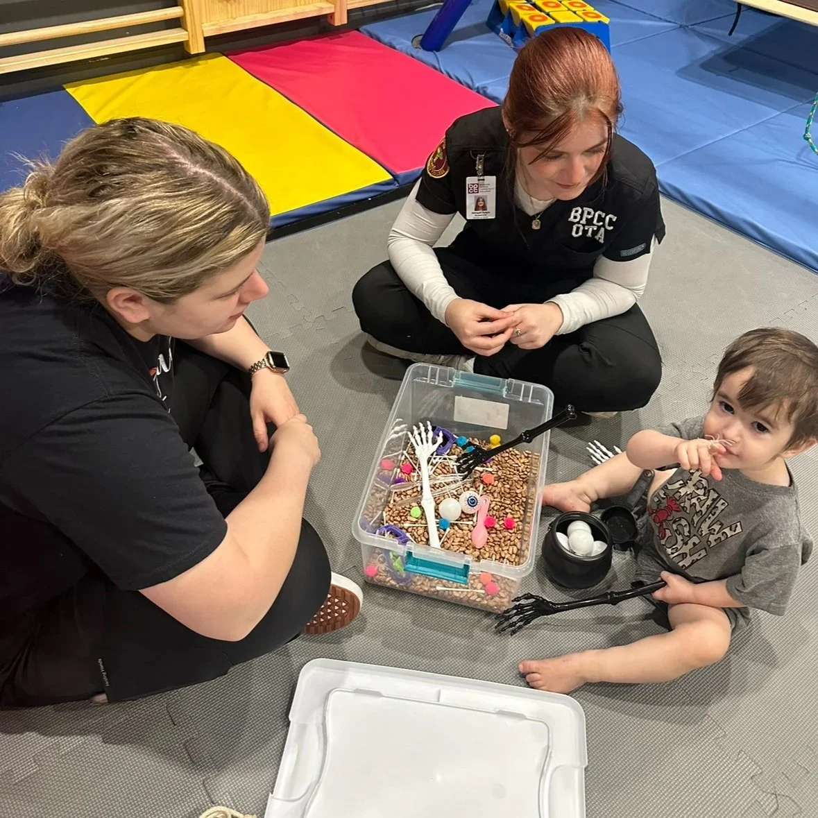 A FUNdamental therapist and student working with a child during a sensory bin activity