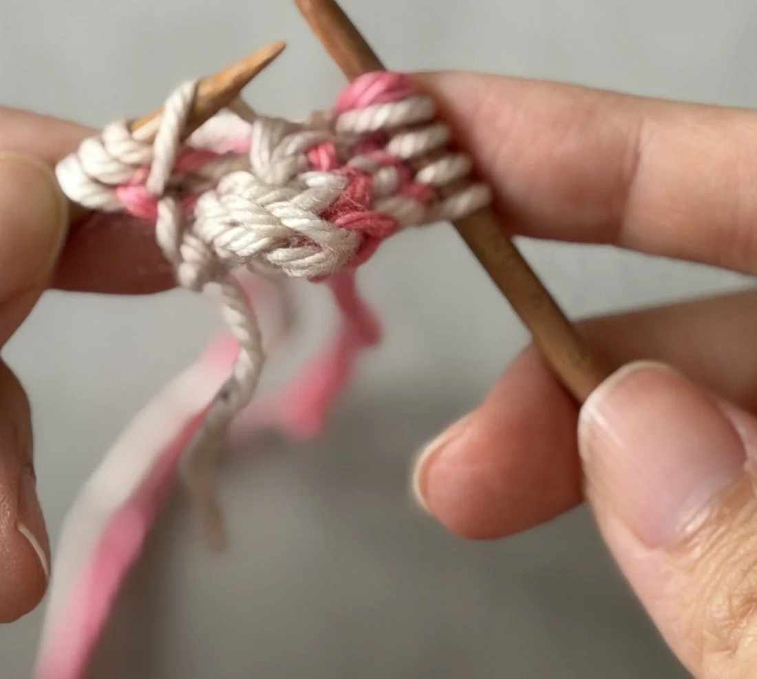 Close-up: The white CC bar lifted onto the left needle beside the three edge stitches.