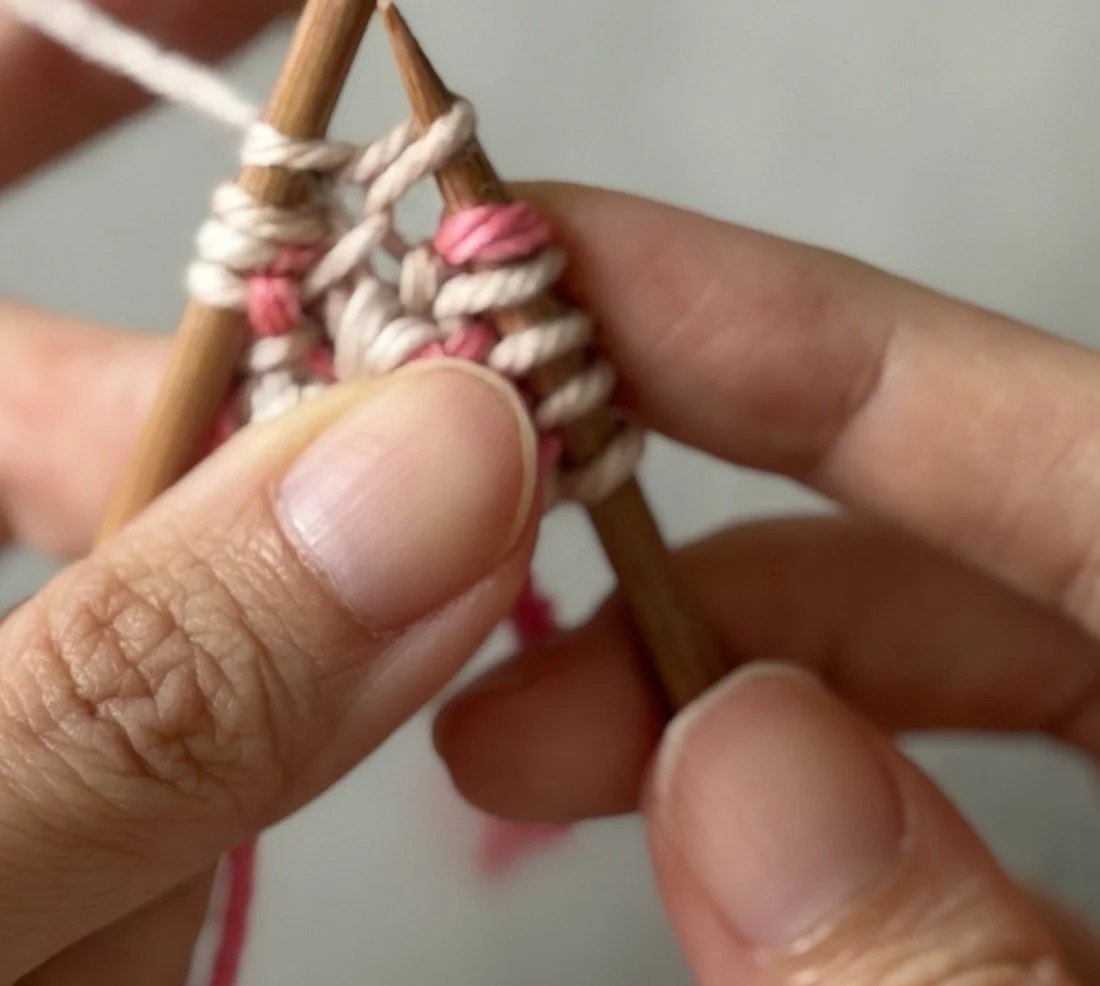 Close-up: White CC working yarn used to knit the lifted bar beside the edge.