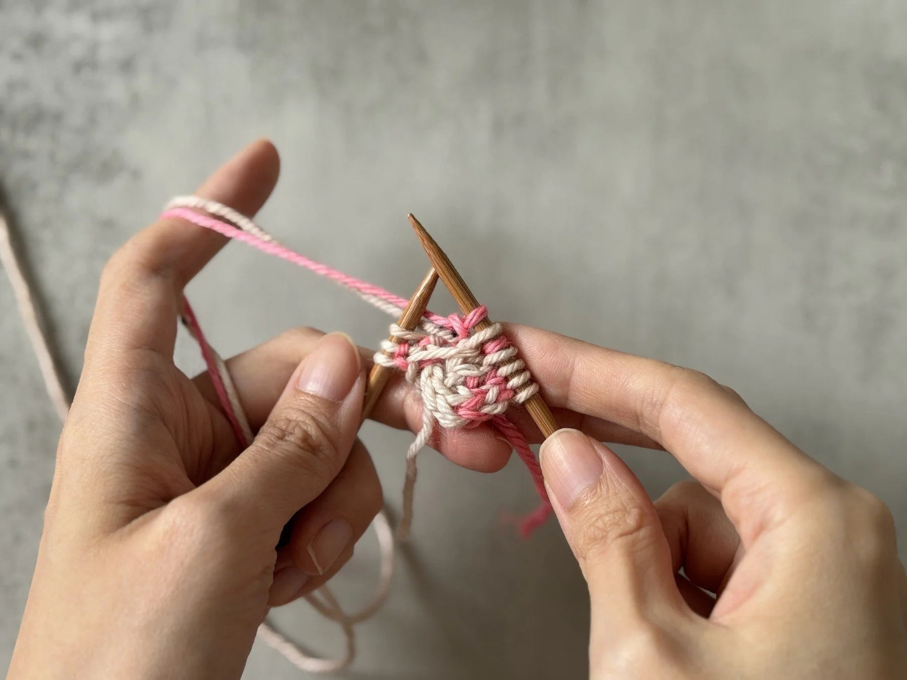 The completed CC knit and MC purl increase pair immediately inside the I-cord edge.