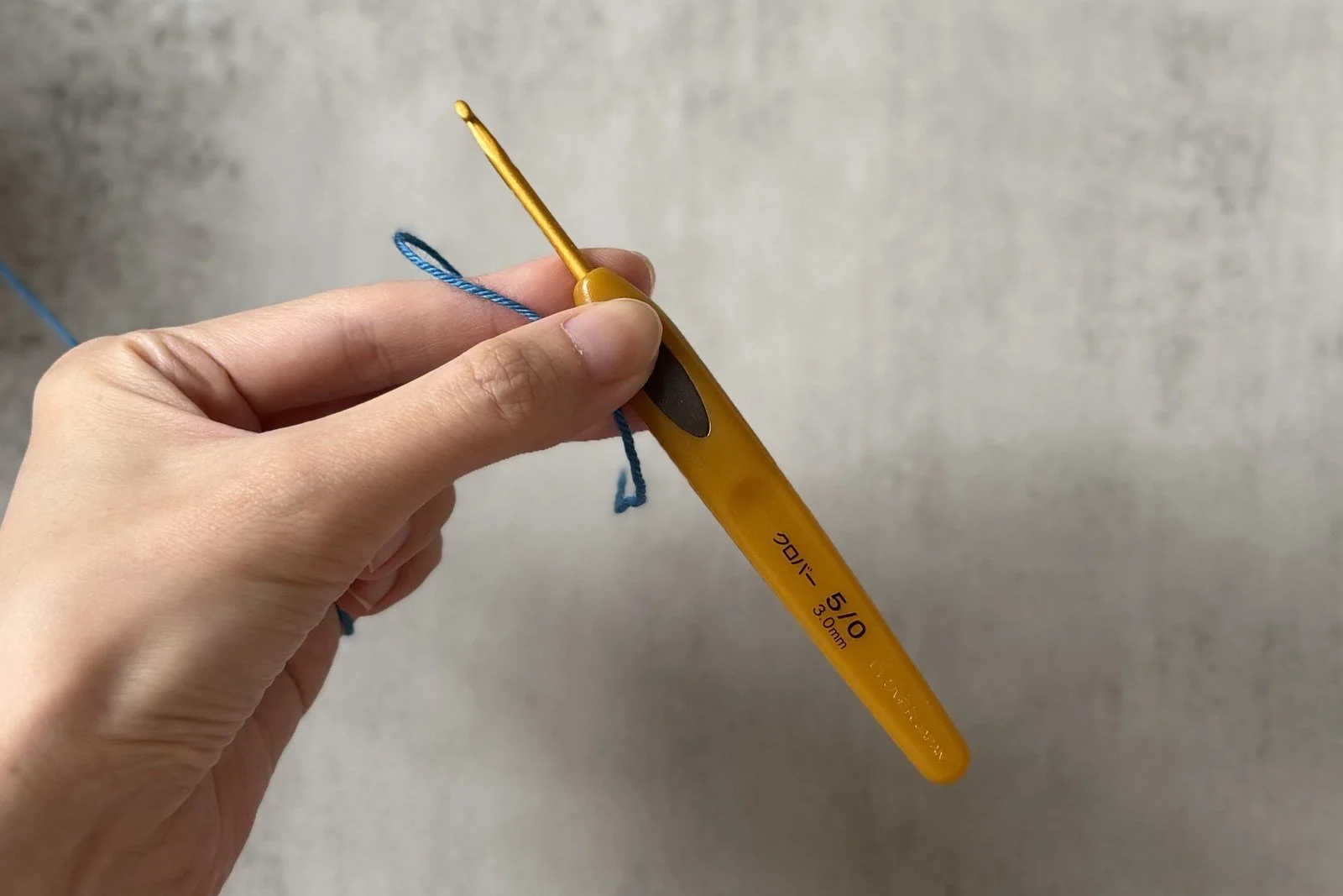 A blue waste-yarn loop held on a crochet hook before making the chain.