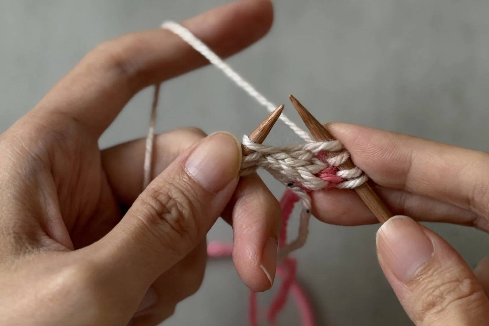 The needle lifting a white strand from the reverse side of the I-cord beside the centre pickup.