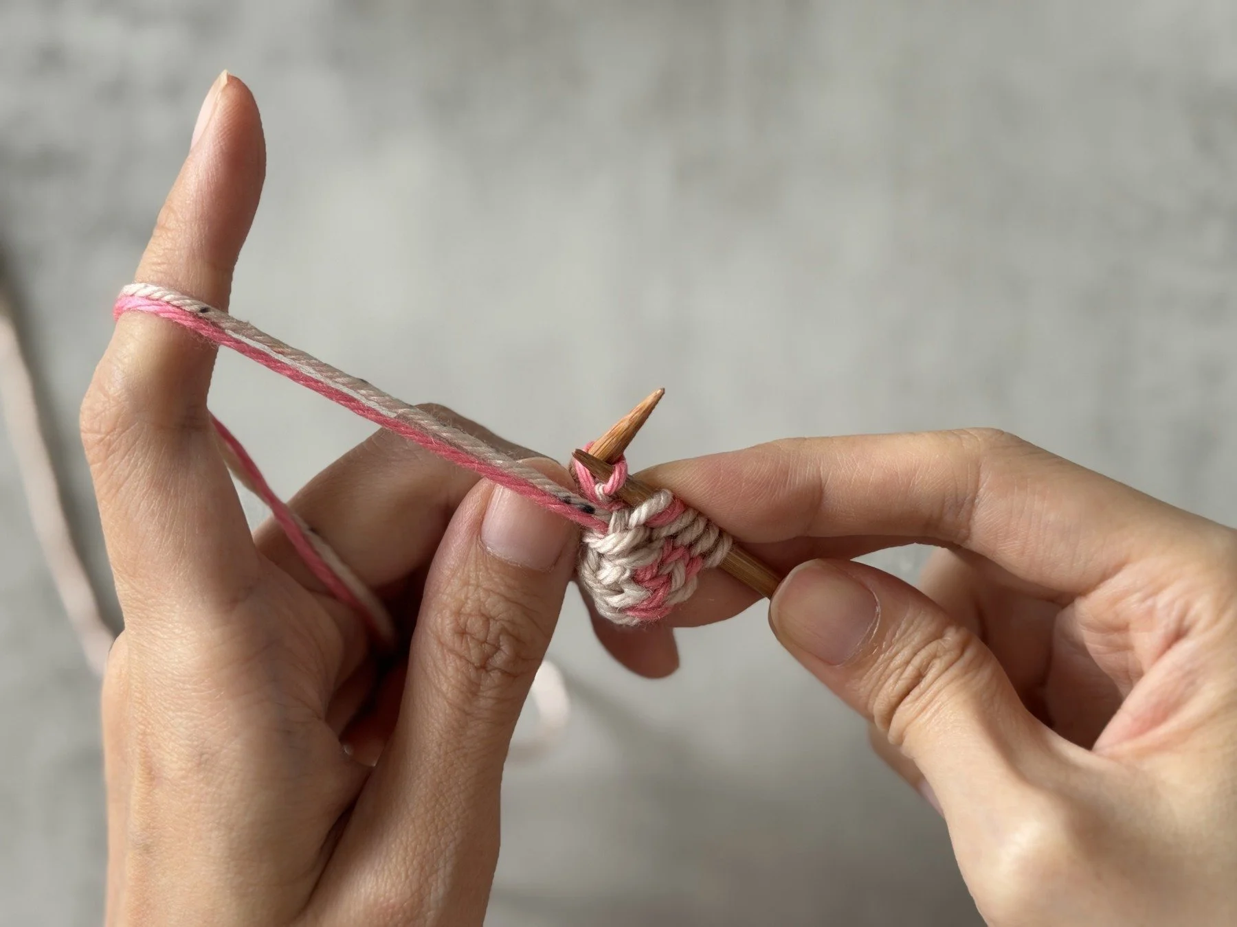Pink MC yarn used to purl through the back loop of the lifted bar.