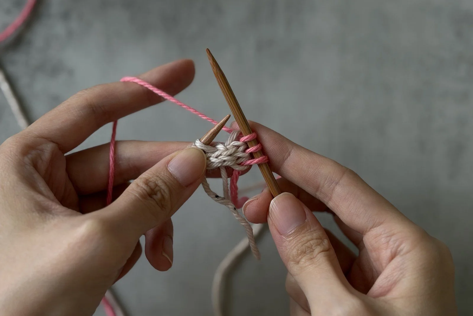 Pink MC being knitted into the first three white edge stitches after sliding the work.