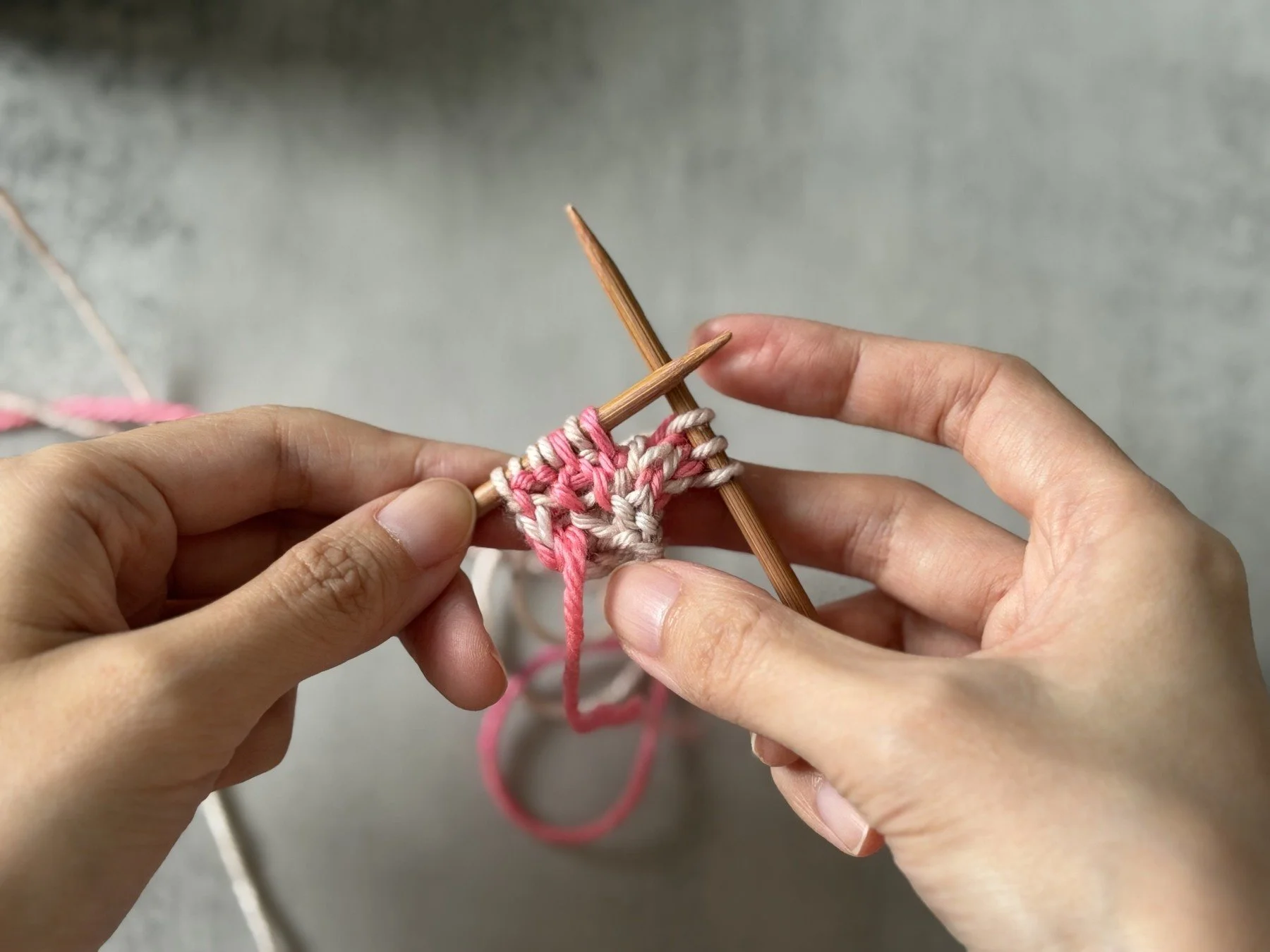 Reverse view of the new increase beside the edge, with pink stitches facing the viewer.