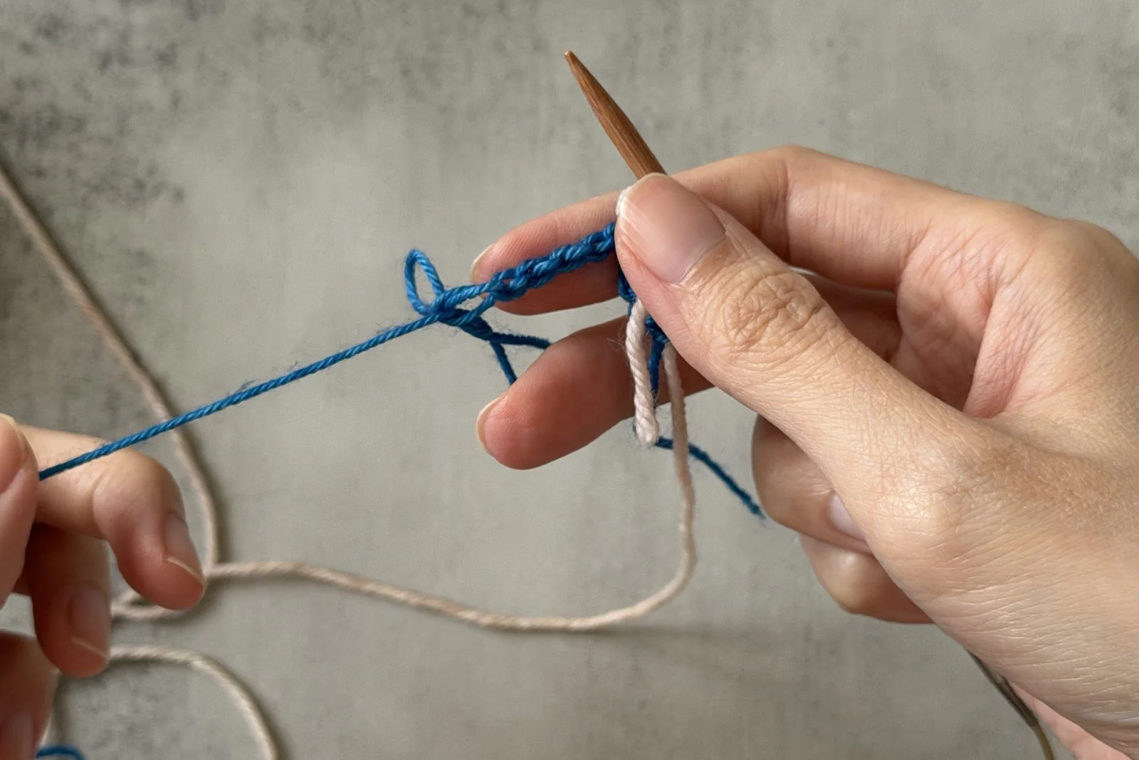 The blue finishing chain being pulled away while the white stitches stay on the needle.