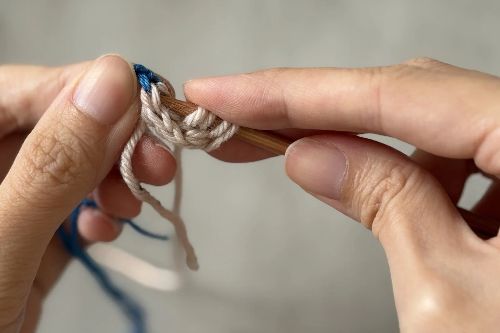 The needle entering a white live stitch beside the blue provisional chain.