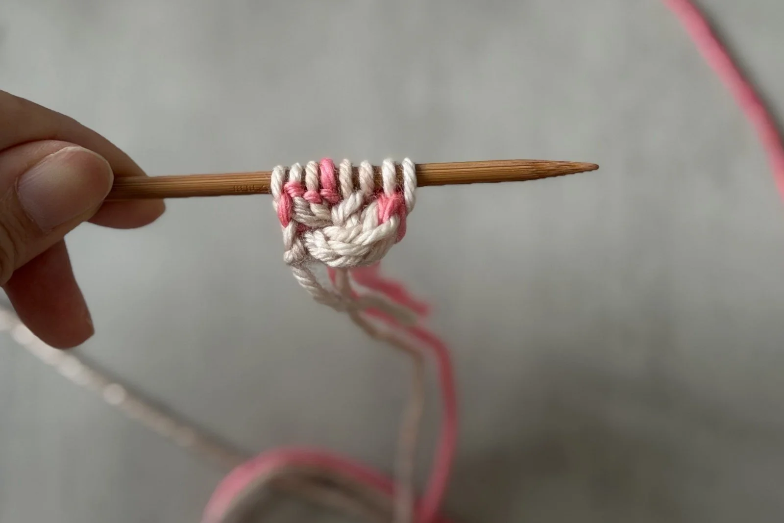 Eight setup stitches on one needle above the small pink and white cast-on tab.
