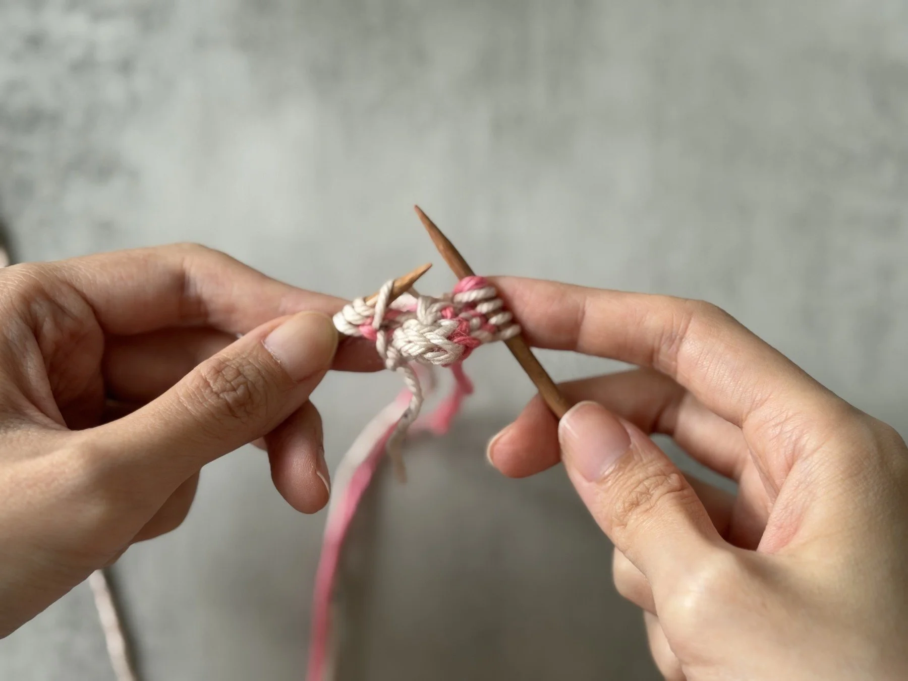 The white CC bar lifted onto the left needle beside the three edge stitches.