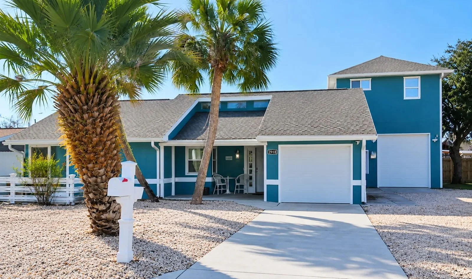 Front exterior of Opal Oasis with palm trees and light gravel landscaping