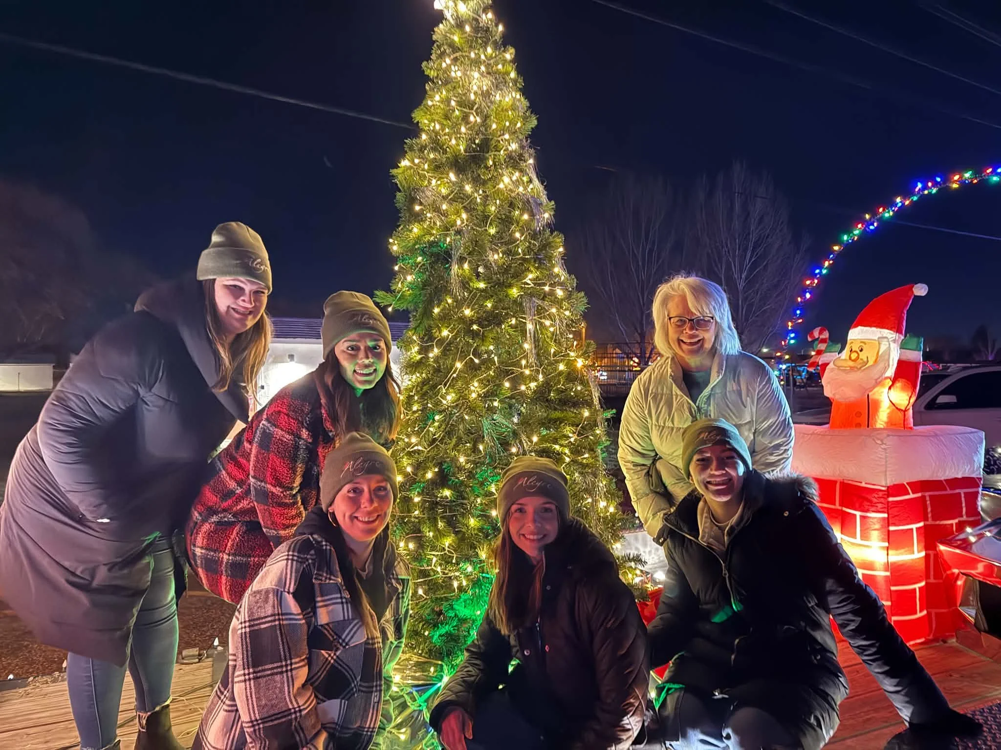 The Alegre Foundation team gathered around a lit Christmas tree
