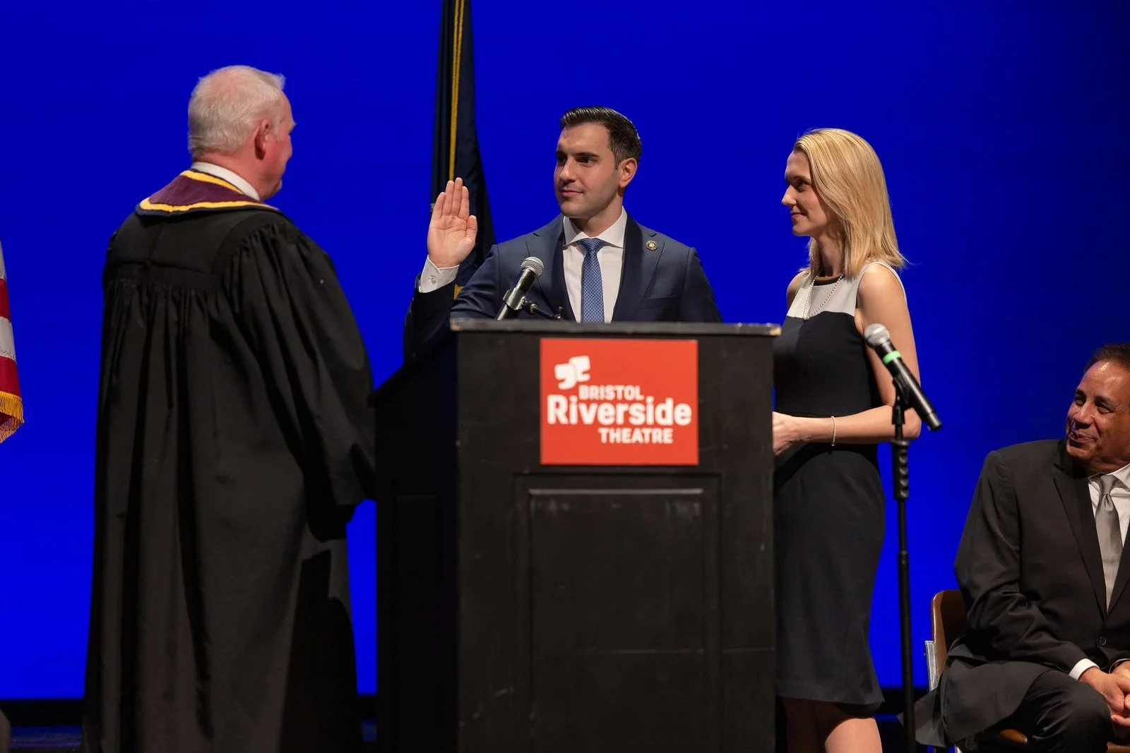 Danny Ceisler taking the oath of office with his right hand raised, his wife Helen beside him