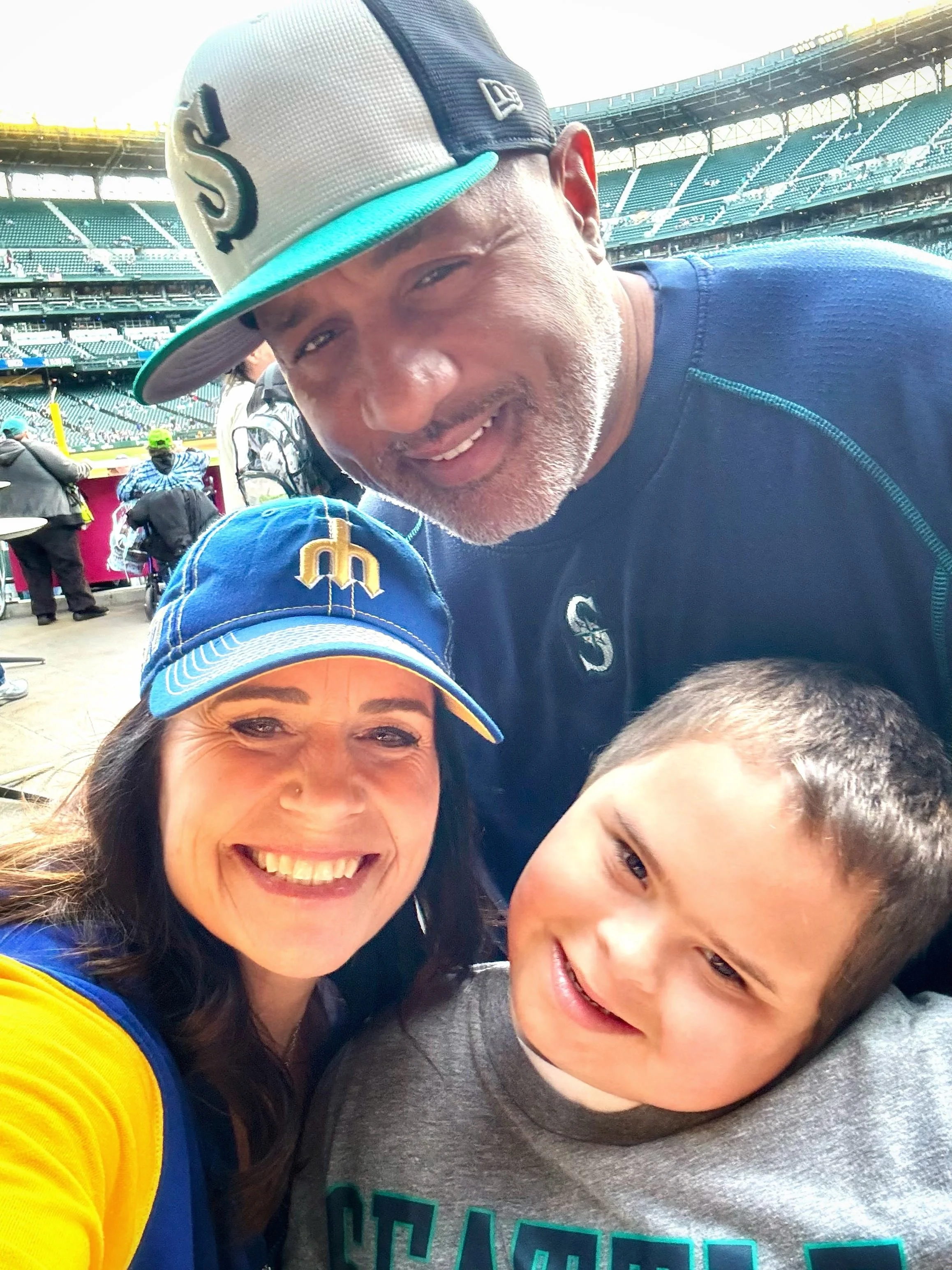A family smiling together at a Seattle Mariners baseball game