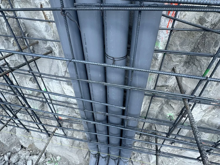 Grey electrical conduits routed through a reinforced construction area.