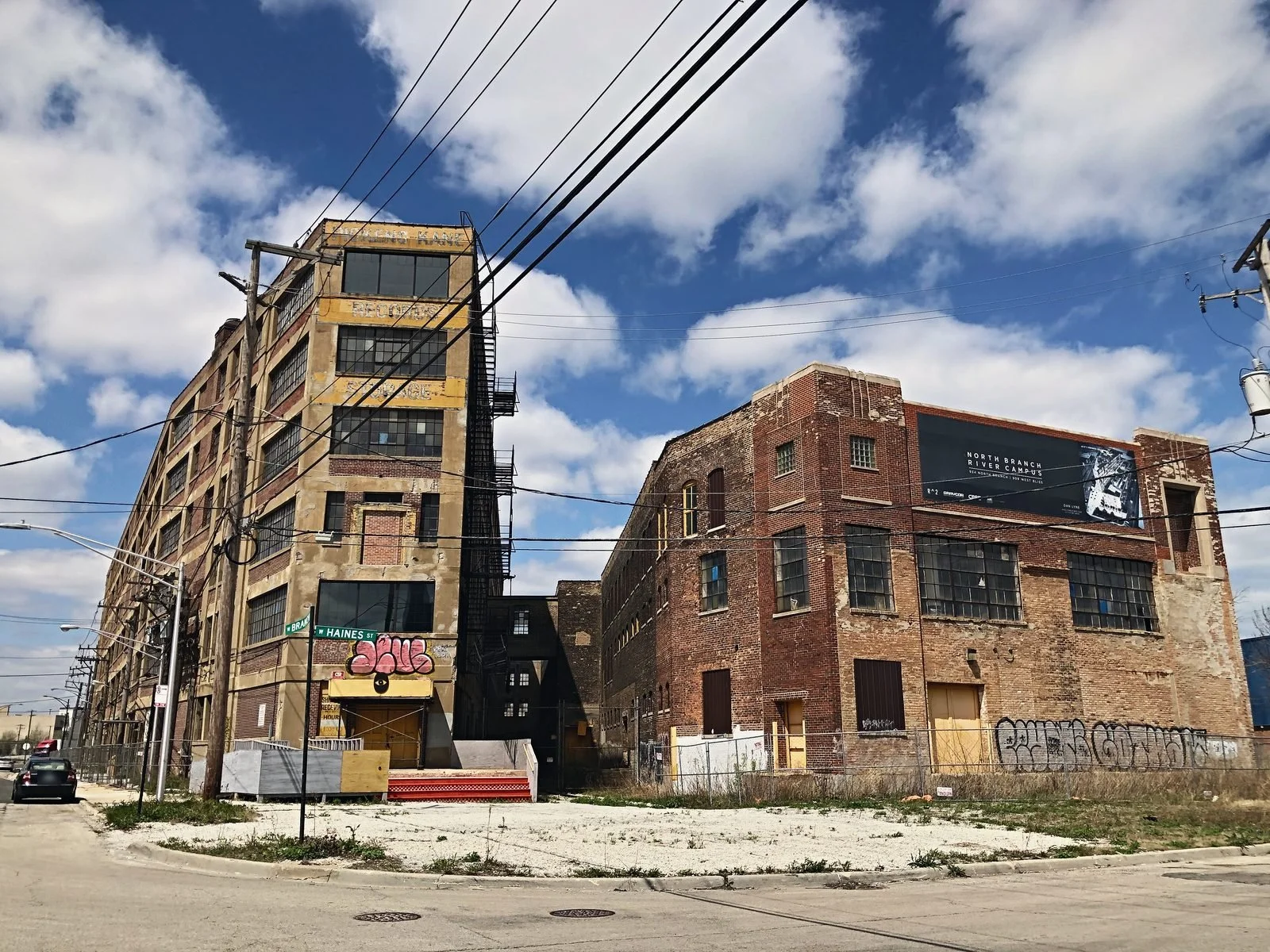 Two vacant brick industrial buildings beside an empty lot on a city corner