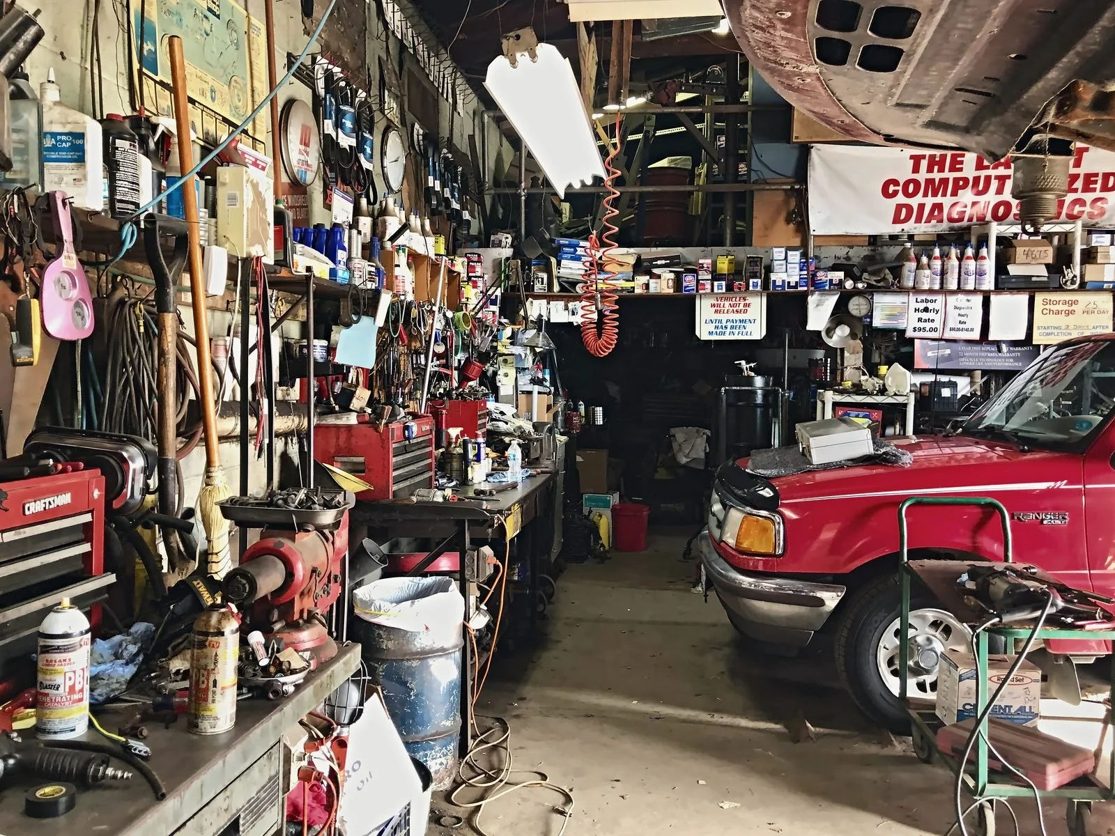 Cluttered working auto repair garage with tool benches and a red pickup truck
