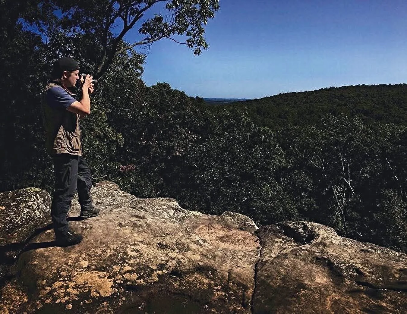 Philip Plowden photographing a forested valley from a sandstone bluff in Southern Illinois