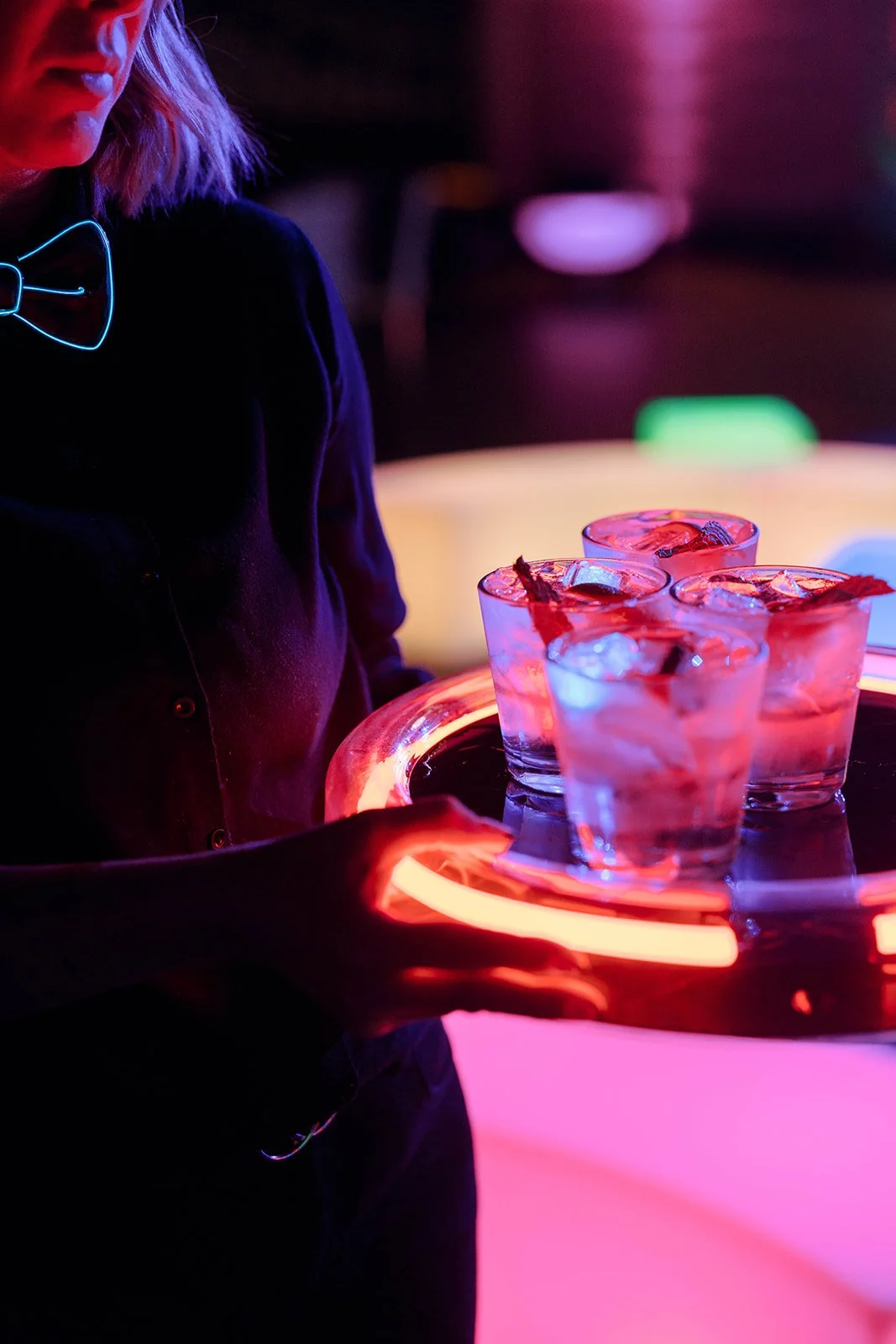 Server presenting cocktails on an illuminated tray