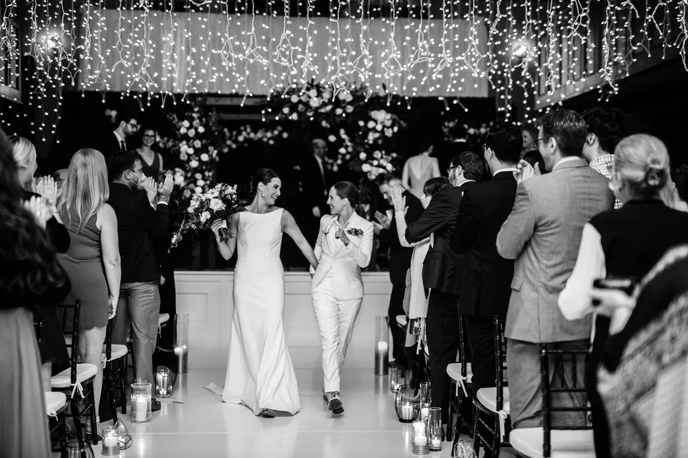 Newlyweds walking through applauding guests