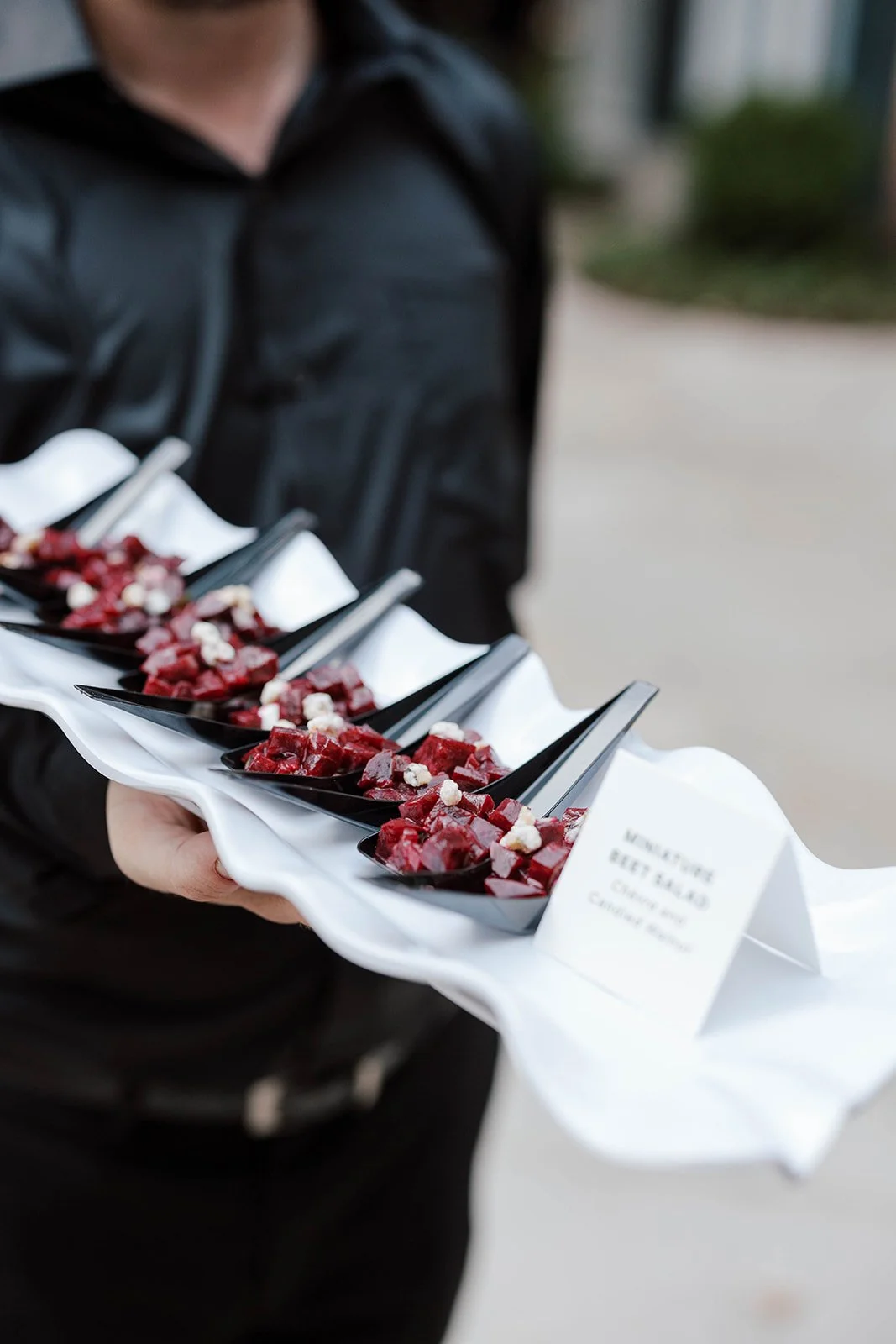 Server presenting individual beet salad appetizers