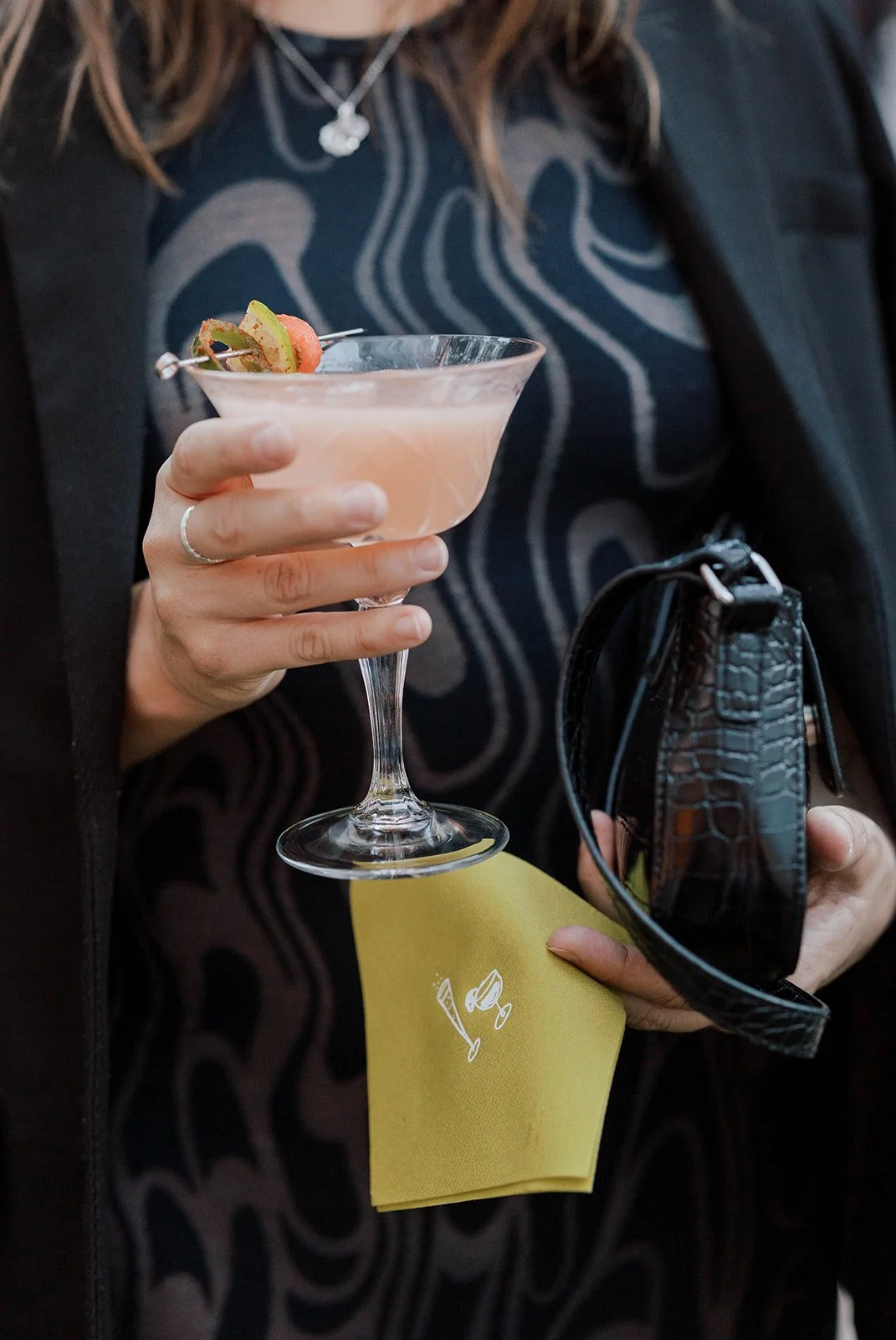 Guest holding a pink cocktail with citrus garnish