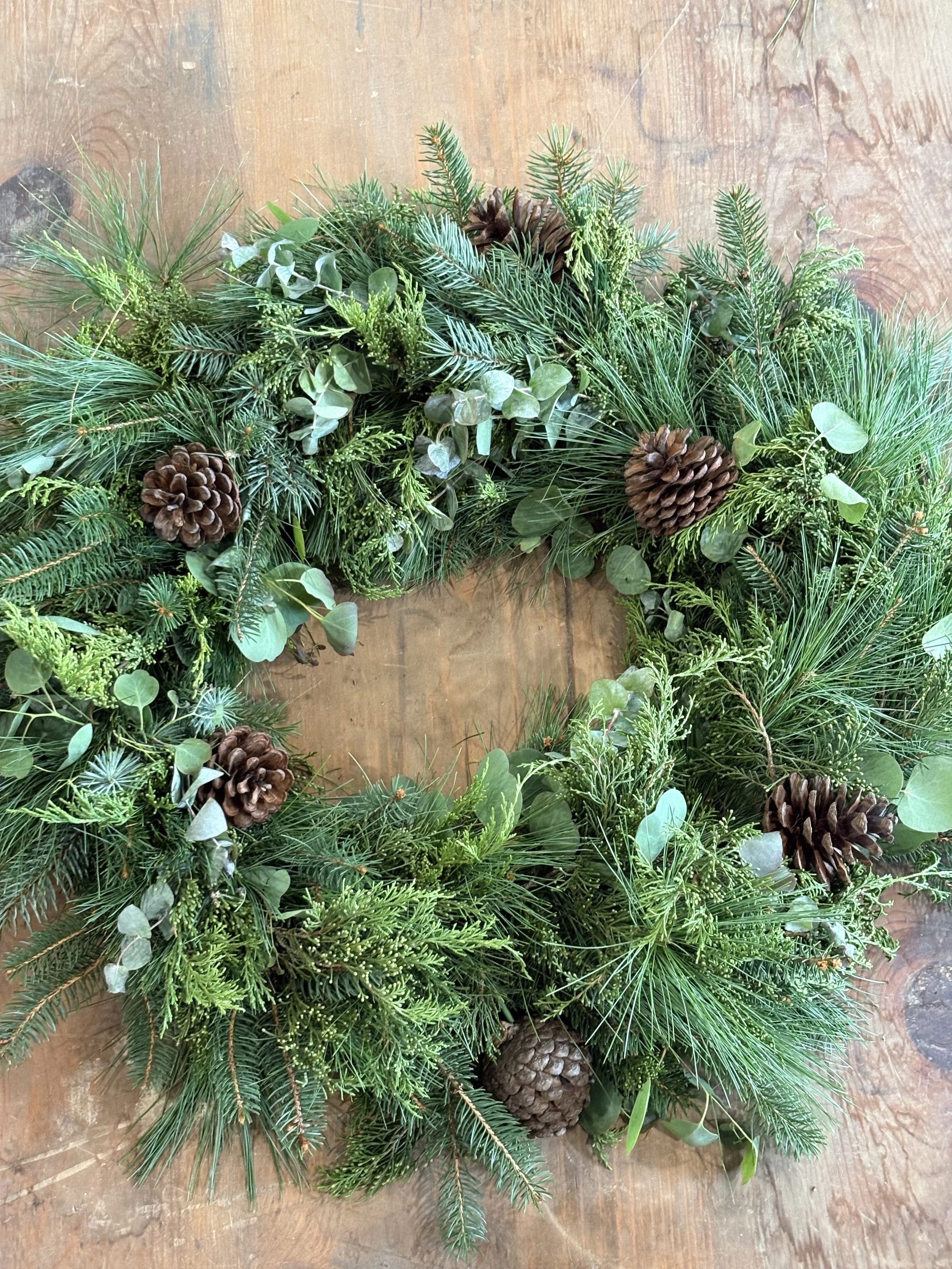 Handmade evergreen wreath with eucalyptus and pinecones arranged around the wreath