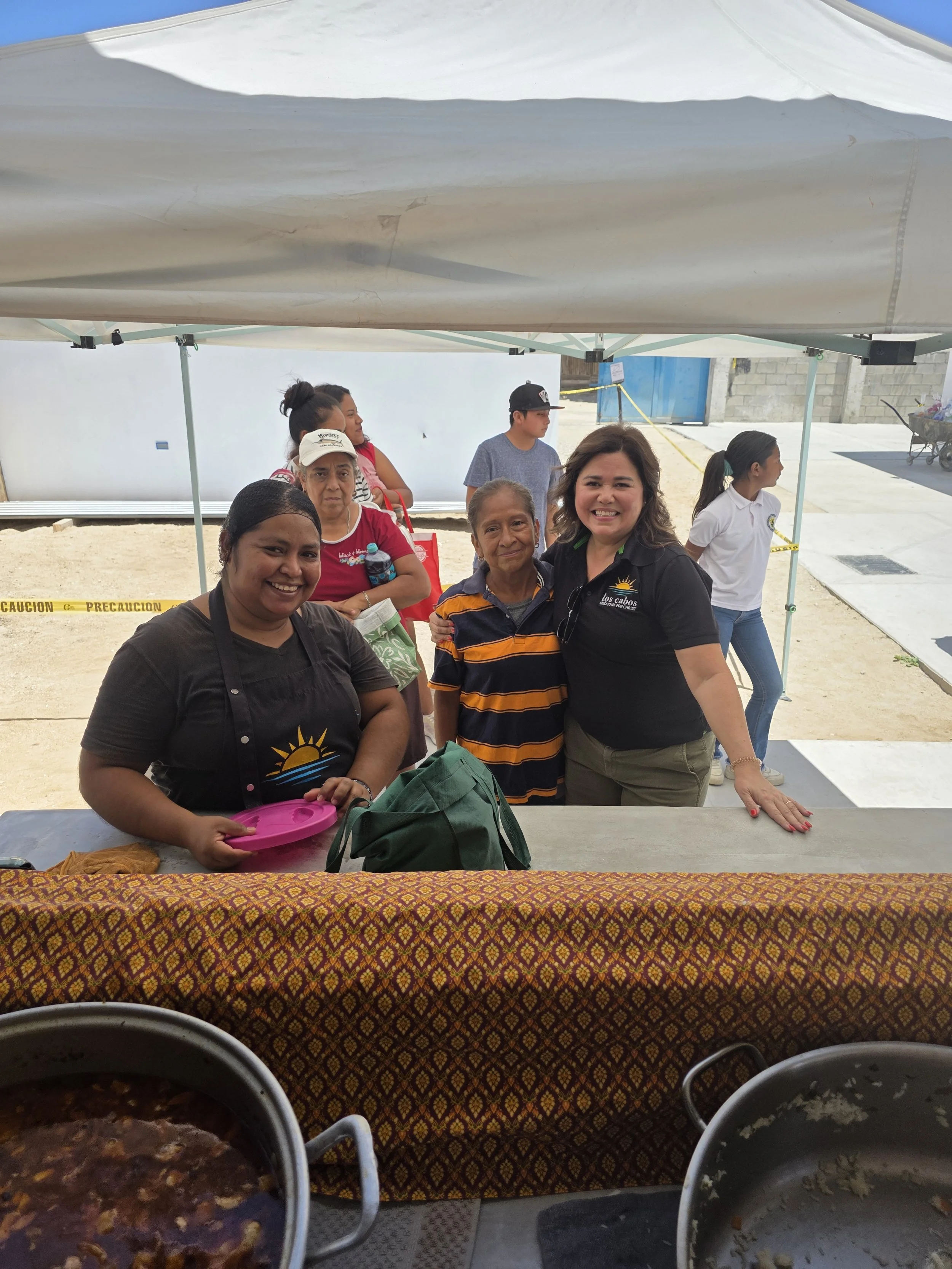 Smiling members of the serving team behind the food table at the Community Center.