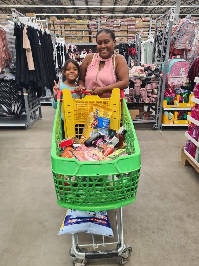 A mother and daughter with a cart of groceries during the August family sponsorship shopping trip.